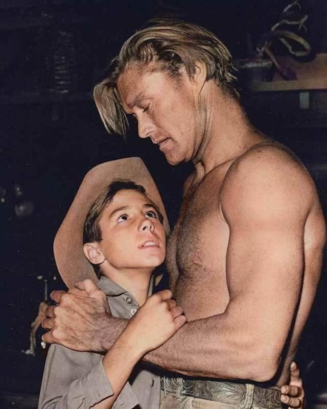 Chuck Connors embracing his on-screen son, Johnny Crawford, in a heartfelt father-son moment from The Rifleman. Their bond on and off-screen created lasting memories for fans of the show.