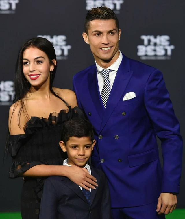 Cristiano Ronaldo, Georgina Rodríguez, and their son pose at an event.